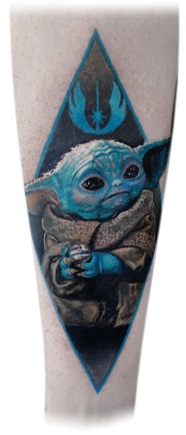 Colour Grogu tattoo framed by a blue diamond and emblem.