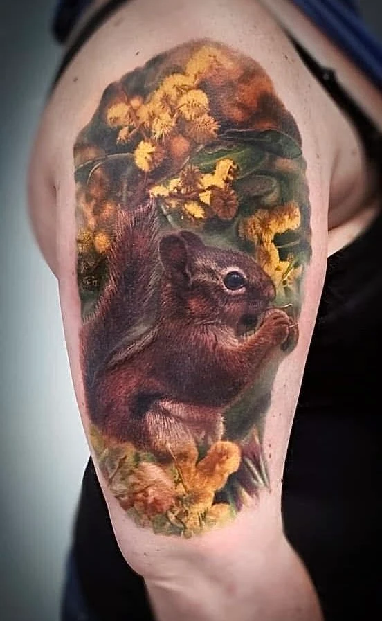 Colour squirrel tattoo surrounded by yellow blossom.