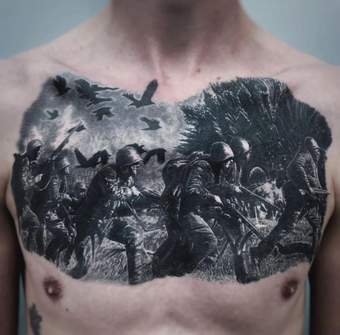 Large black and grey chest tattoo of a detailed battle scene.